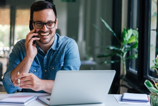 Man talking on the phone while working on his laptop
