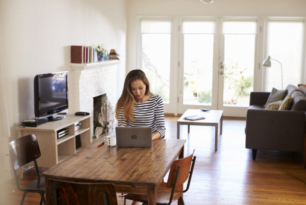 Woman working from home using a laptop on dining table